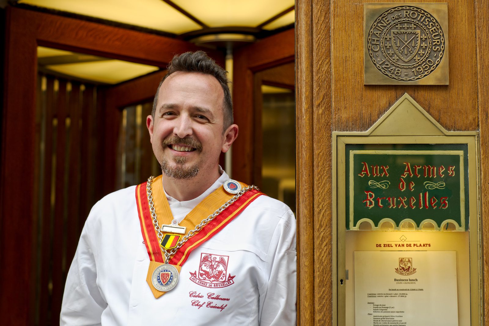Le chef Cédric Callenaere devant la plaque Aux Armes de Bruxelles