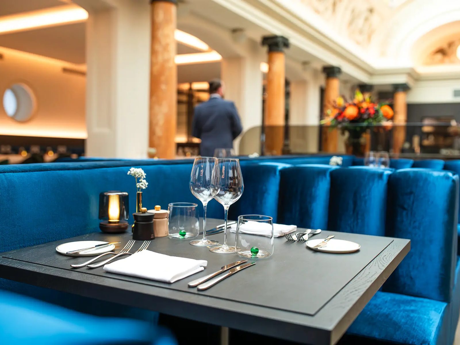 Banquettes de velours bleu et table dressée dans la salle du Belga Queen