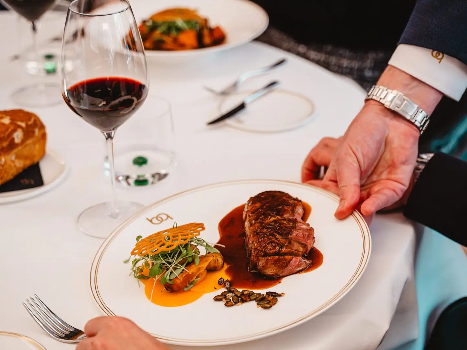 Serveur dressant une assiette devant un client à table au Belga Queen