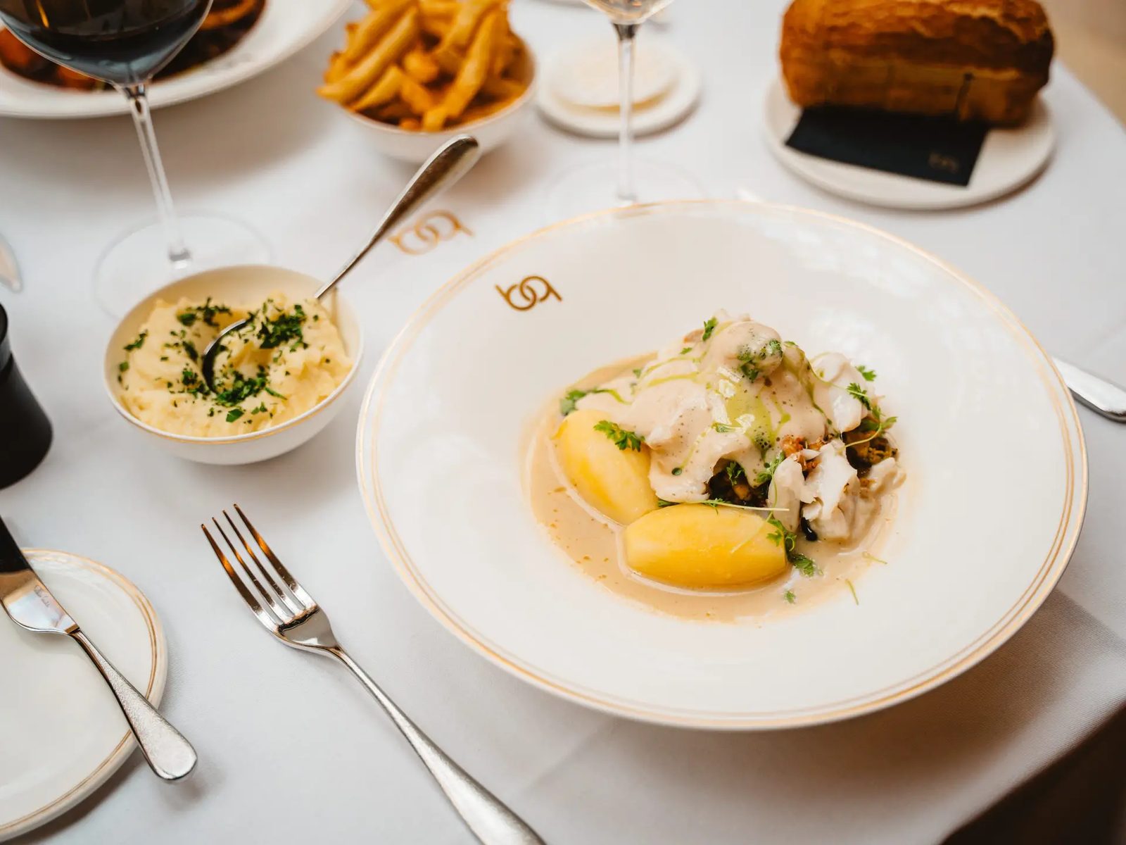 Assiette de poisson en sauce servie avec frites et pain au Belga Queen