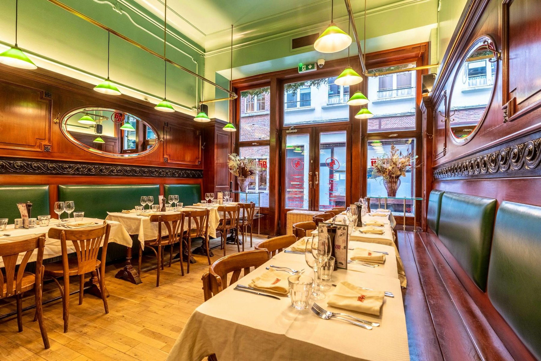 Salle de Bouillon Bruxelles avec banquettes vertes, miroirs et boiseries de brasserie