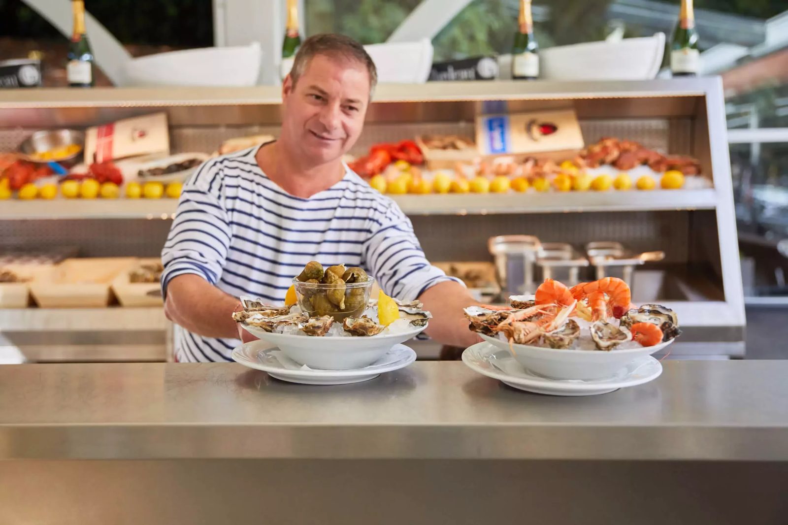 Portrait de José, écailler de la Brasserie de la Patinoire, présentant une assiette de fruits de mer