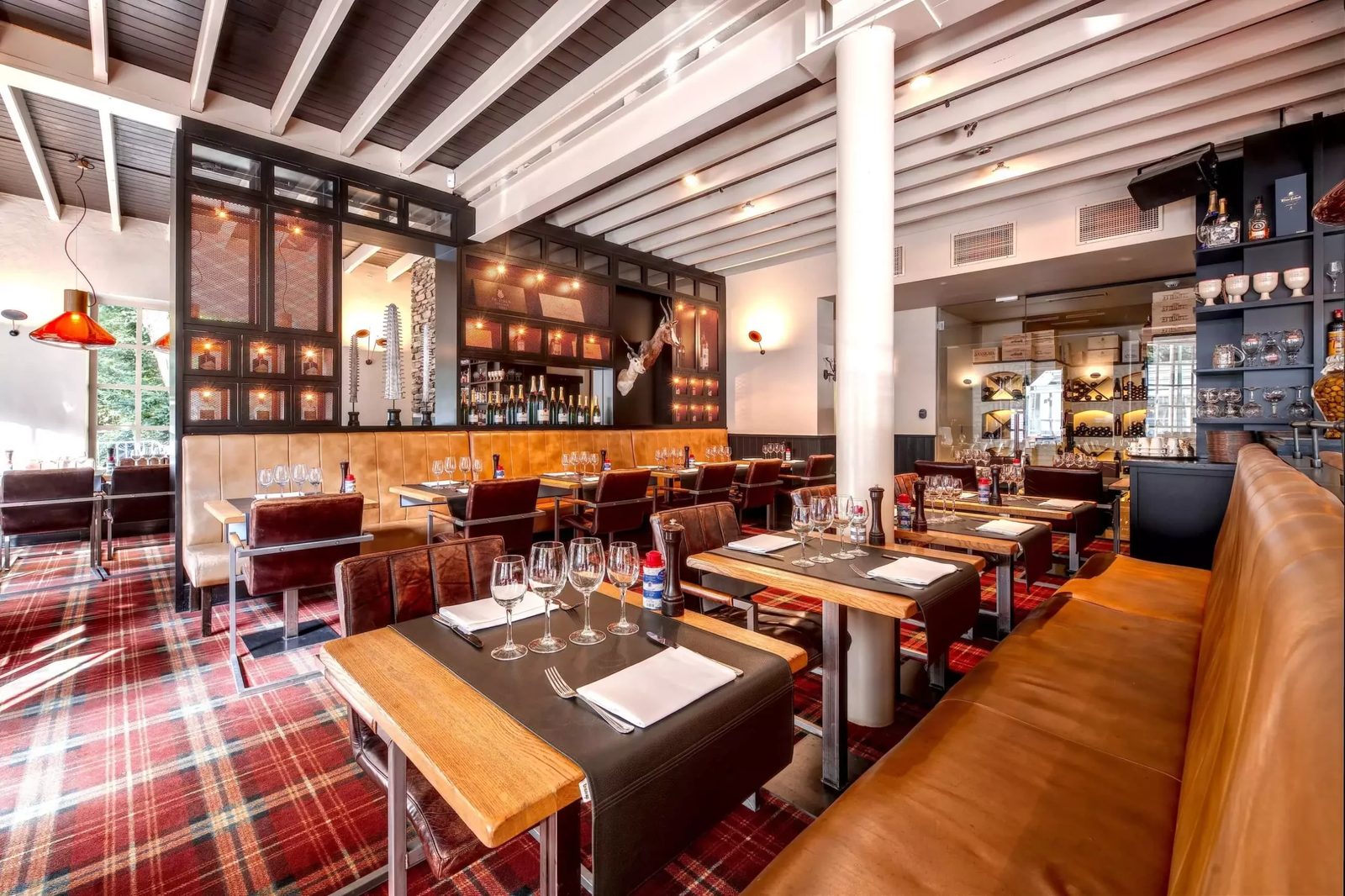 Banquettes et tables de la brasserie sous les suspensions ambrées