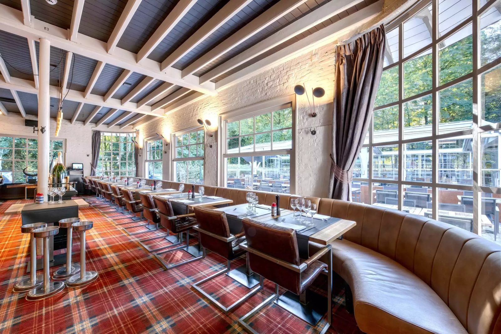 Salle véranda de la Brasserie de la Patinoire avec grandes baies vitrées sur le bois