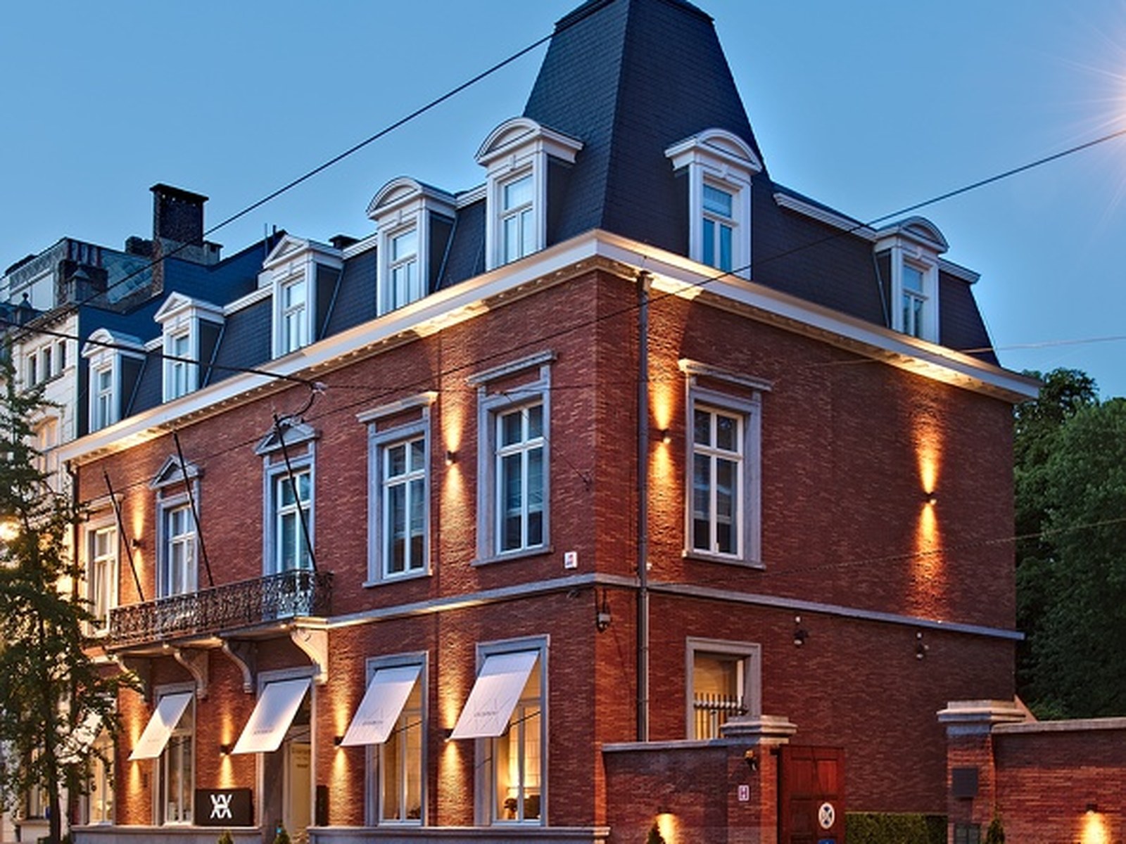 Façade en briques rouges de la maison de maître du restaurant Brugmann, éclairée le soir