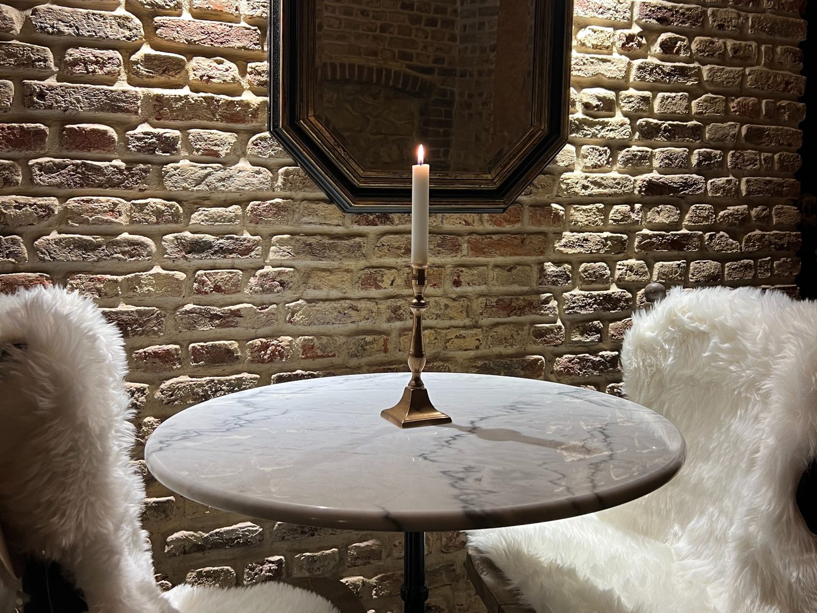 Table en marbre et mur de briques anciennes chez Celi's Resto