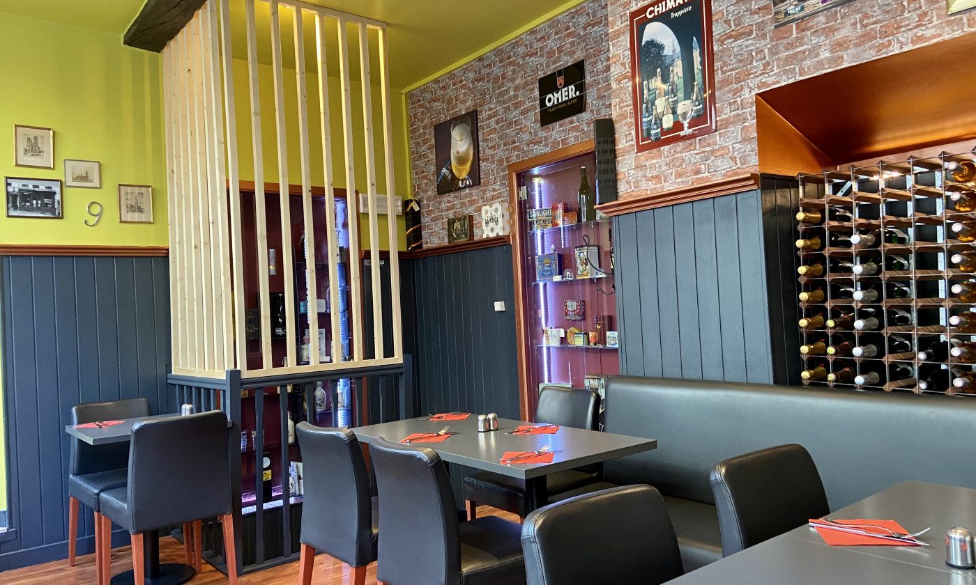 Salle de C'est bon c'est belge avec banquettes, murs jaunes et casiers à vins