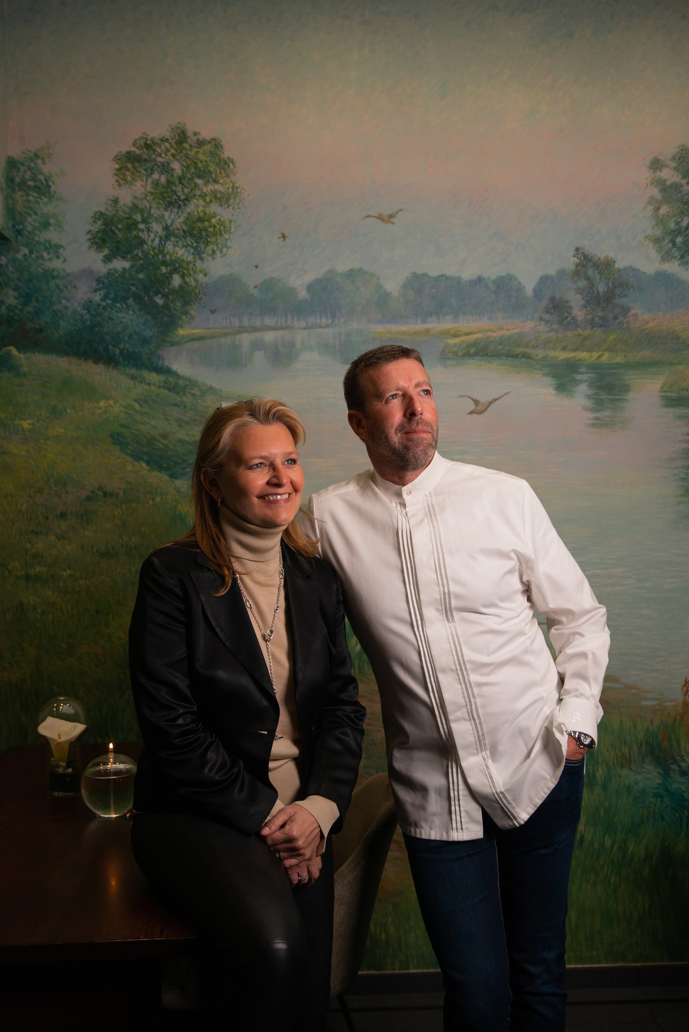 Lionel Rigolet en veste de chef et Laurence Rigolet devant la fresque du restaurant