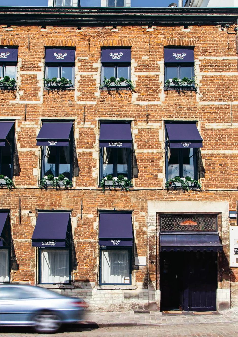 Façade en briques et stores bleus de L'Écailler du Palais Royal, rue Bodenbroek