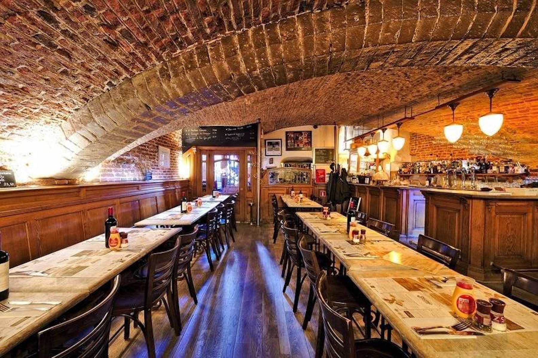 Salle en cave voûtée du XVIIᵉ siècle du restaurant 't Kelderke à Bruxelles, longues tables en bois