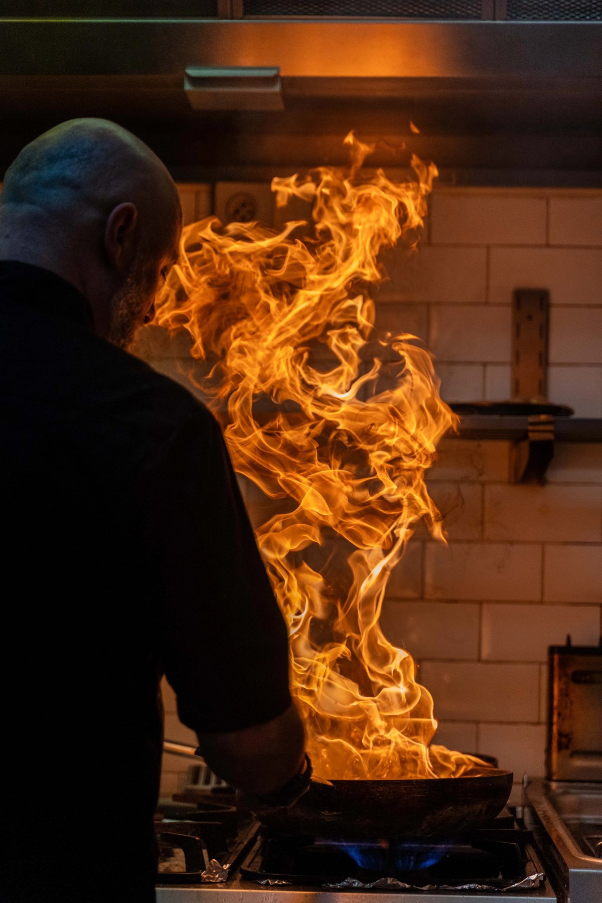 Chef de La Pierre Bleue flambant un plat en cuisine