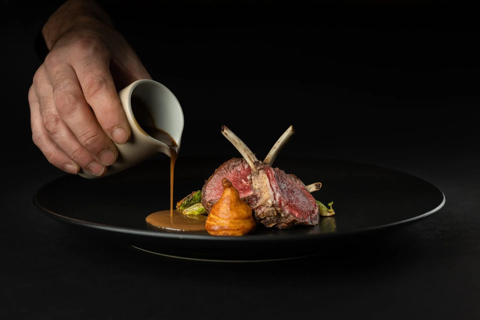 Dressage d'un plat de viande avec sauce versée à La Table de Mus