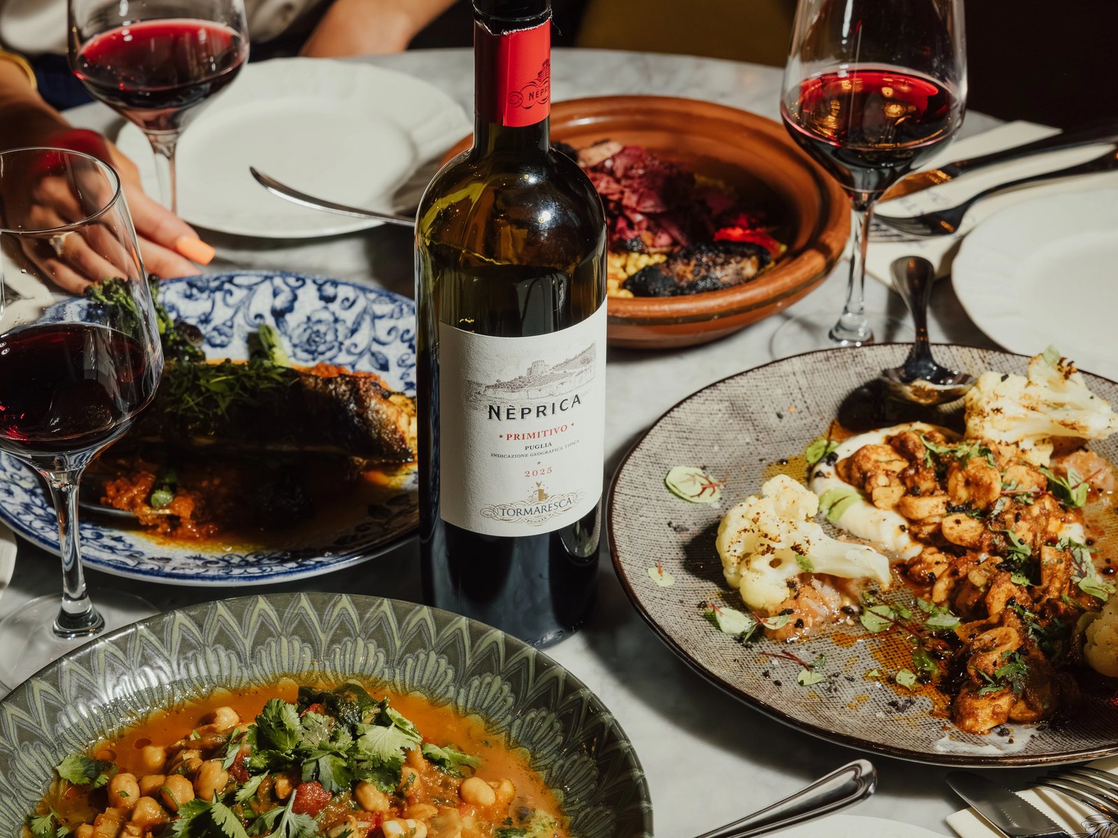 Plats méditerranéens et bouteille de vin rouge sur une table du Conteur