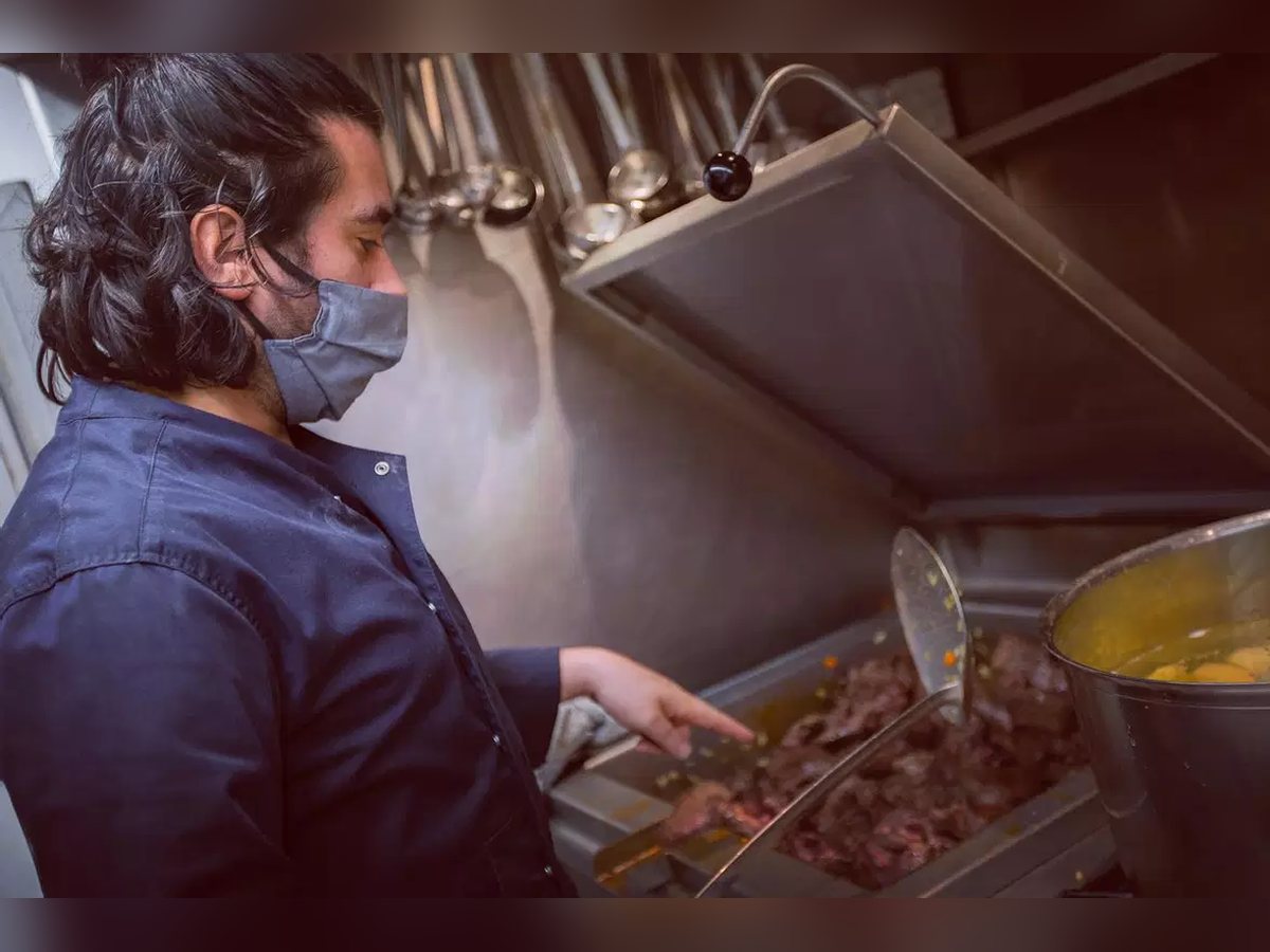 Un cuisinier du Grand Café dresse un plat en cuisine
