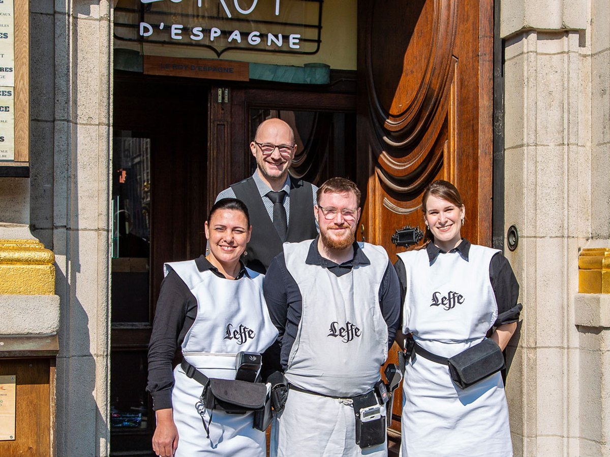 Quatre membres de l'équipe du Roy d'Espagne devant la porte de la brasserie
