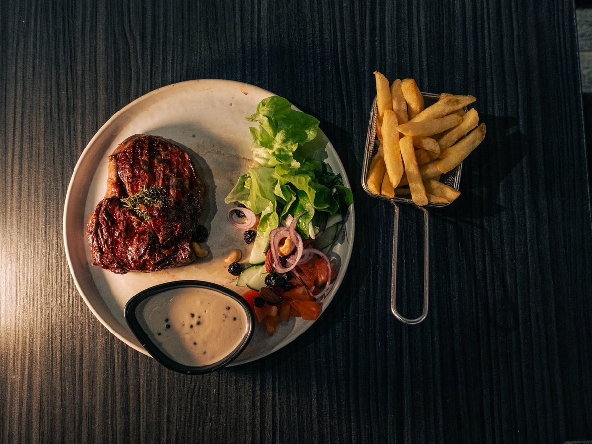Pièce de viande grillée servie avec frites maison et salade au Vintage
