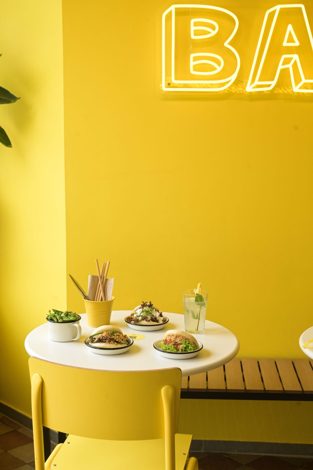 Table et chaises jaunes de Lil Bao sous le néon BAO