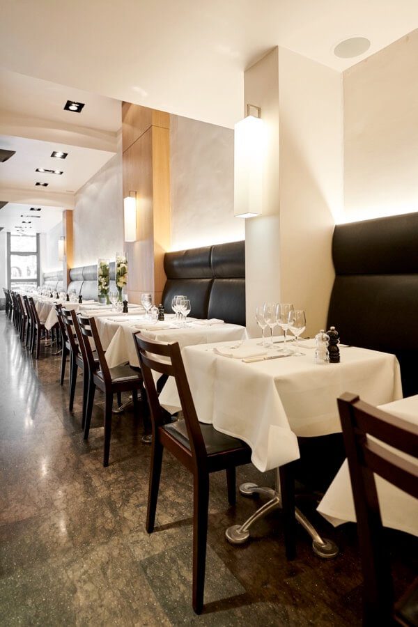 Banquettes et tables dressées dans la salle de Lola au Sablon