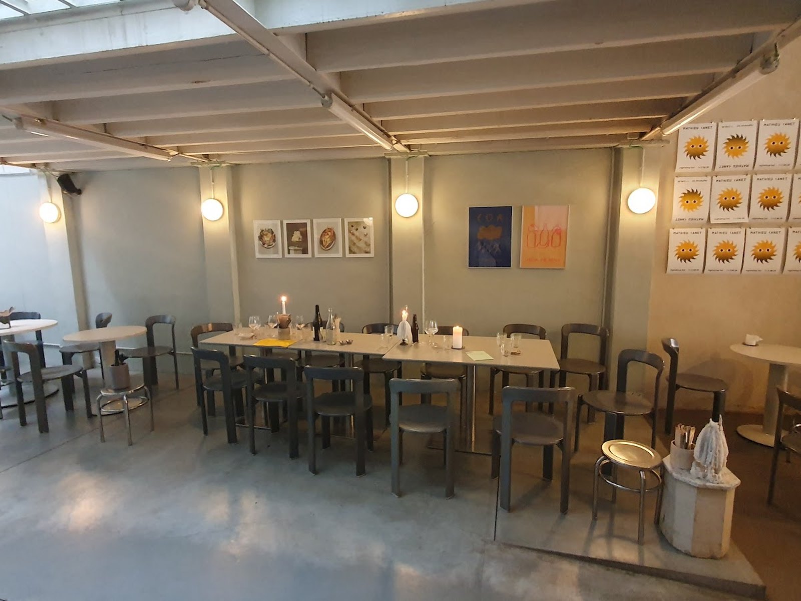 La salle de Nightshop, ancien hangar en béton avec grande tablée et affiches d'artistes