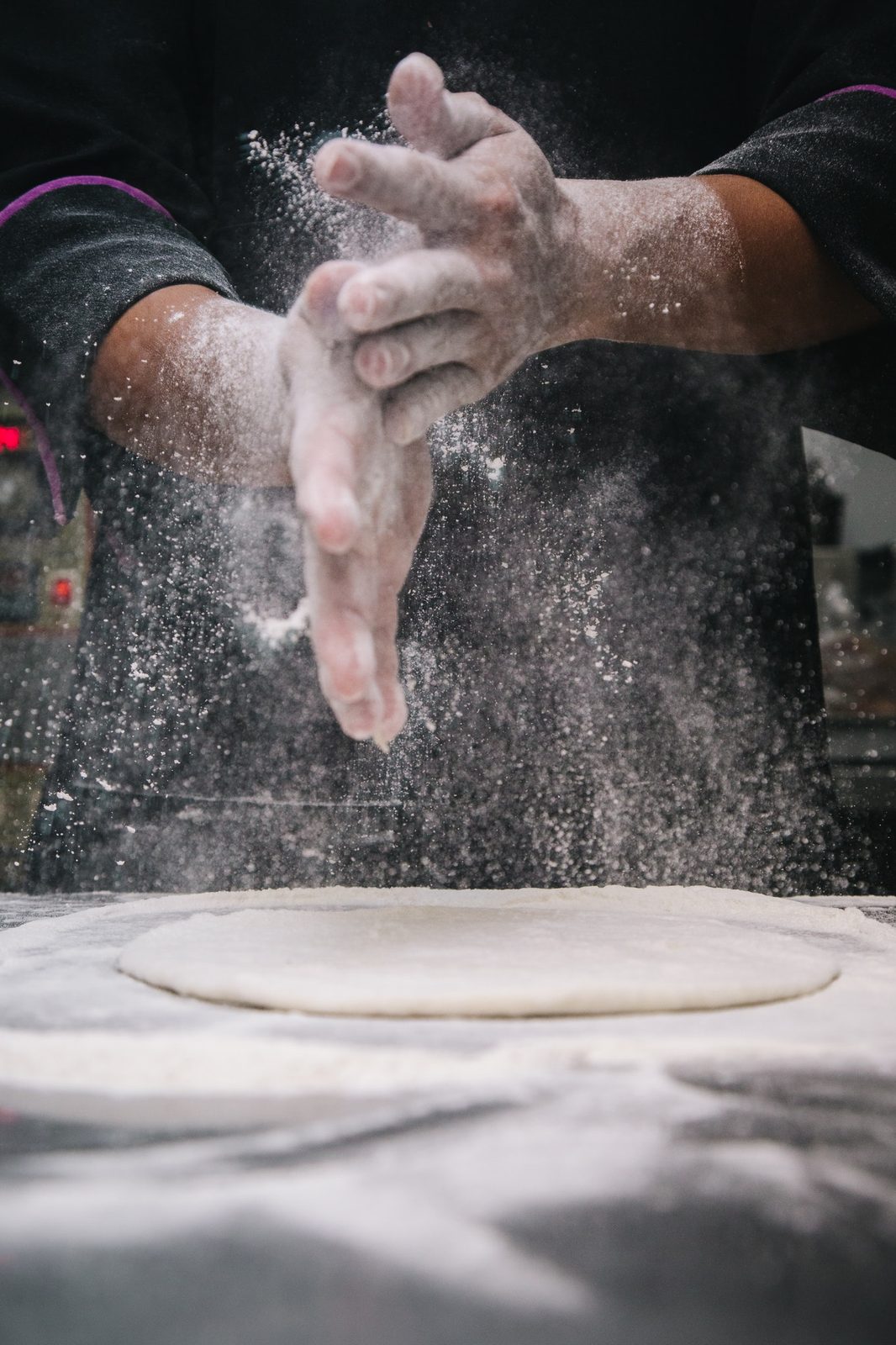 Mains enfarinées travaillant la pâte à focaccia chez NORMA