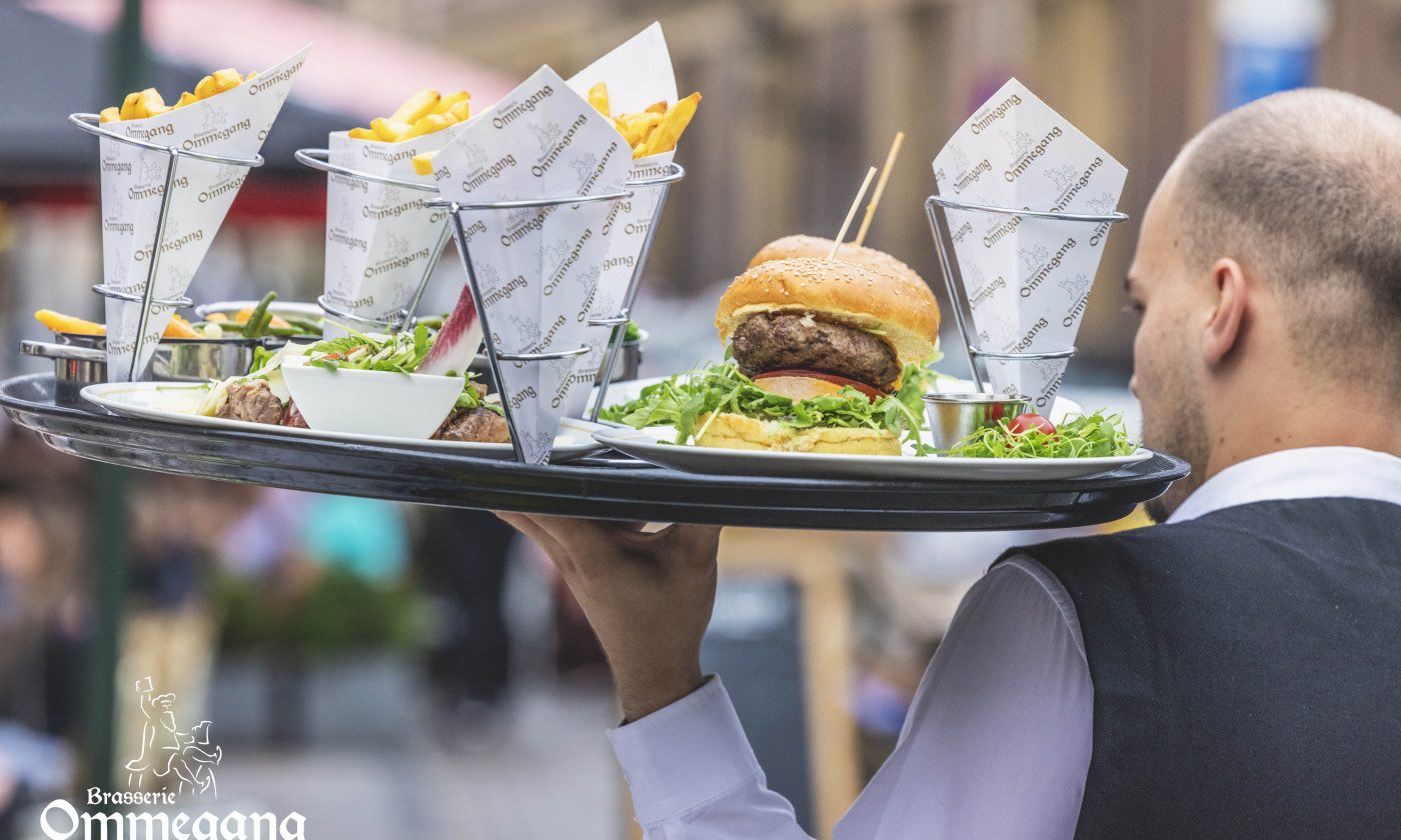 Serveur de la Brasserie Ommegang portant un plateau de burgers et de cornets de frites