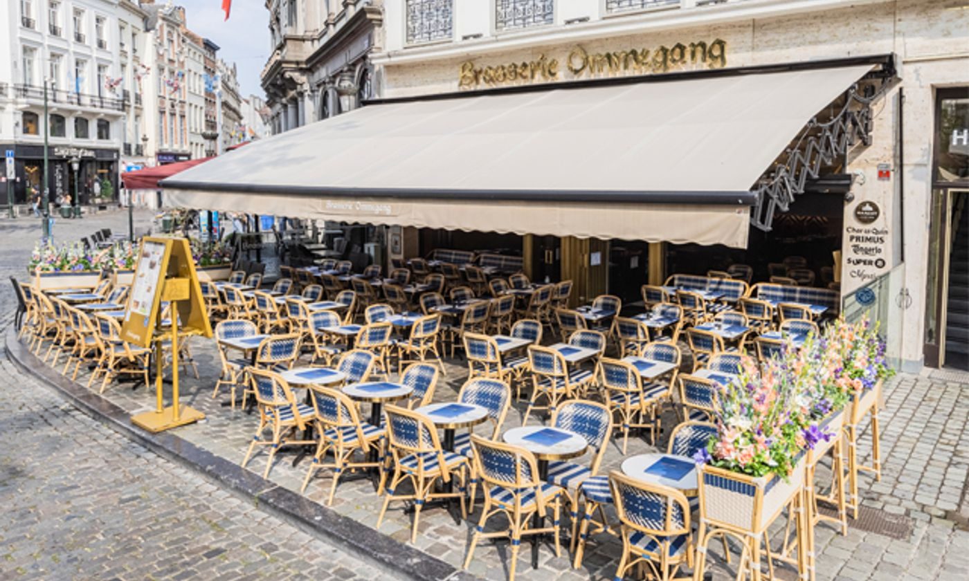 Façade et terrasse de la Brasserie Ommegang avec ses chaises bistrot bleues