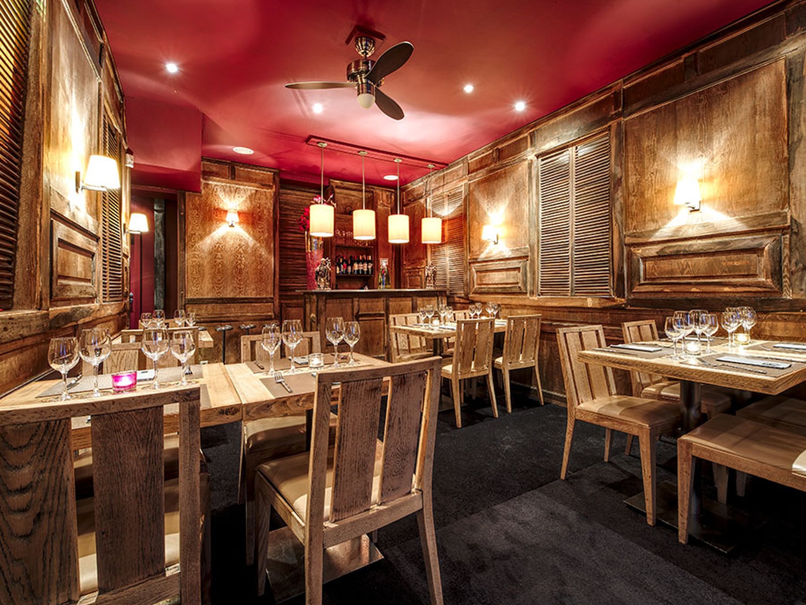 Salle de l'étage de L'Orchidée Blanche, décor colonial en bois et tentures rouges