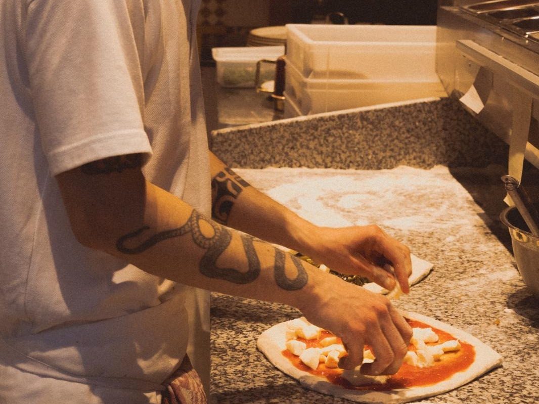 Préparation d'une pizza à la main au laboratoire de la Pizzeria 1032