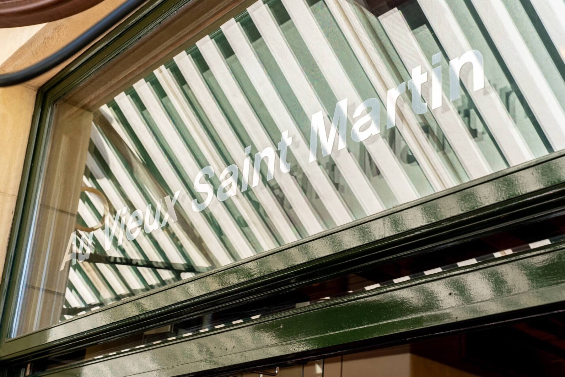Enseigne Au Vieux Saint Martin peinte sur le store rayé du restaurant