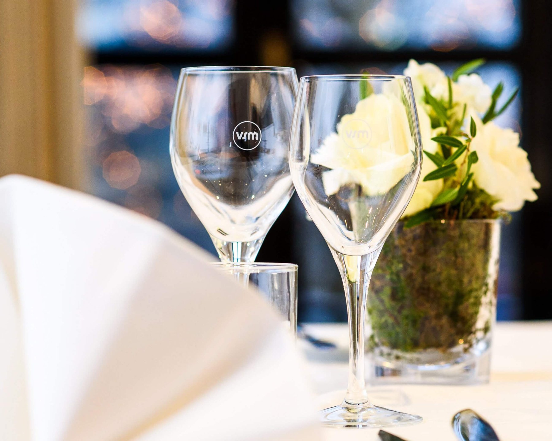 Verres au logo VSM et bouquet blanc sur une table du Vieux Saint Martin