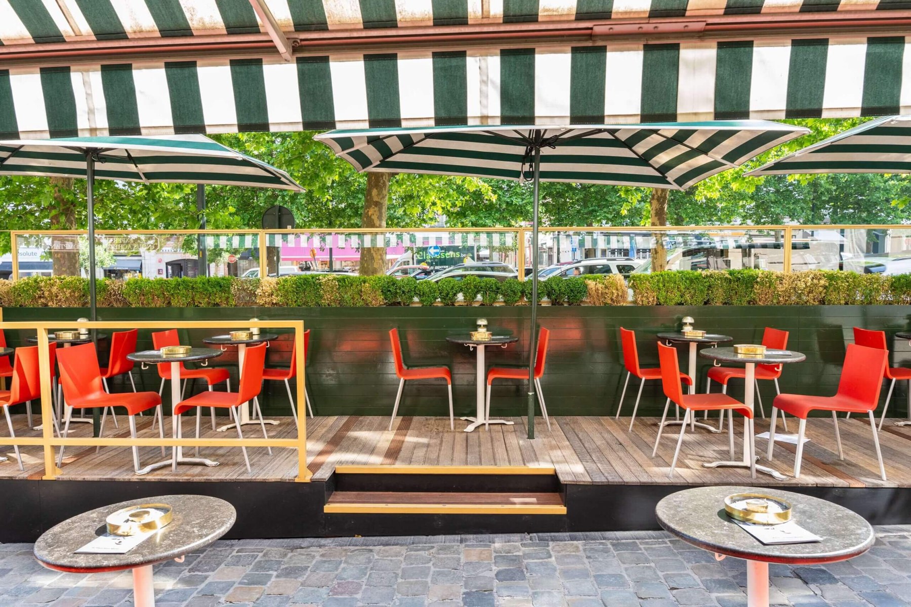 Terrasse d'Au Vieux Saint Martin sous les stores rayés verts et blancs