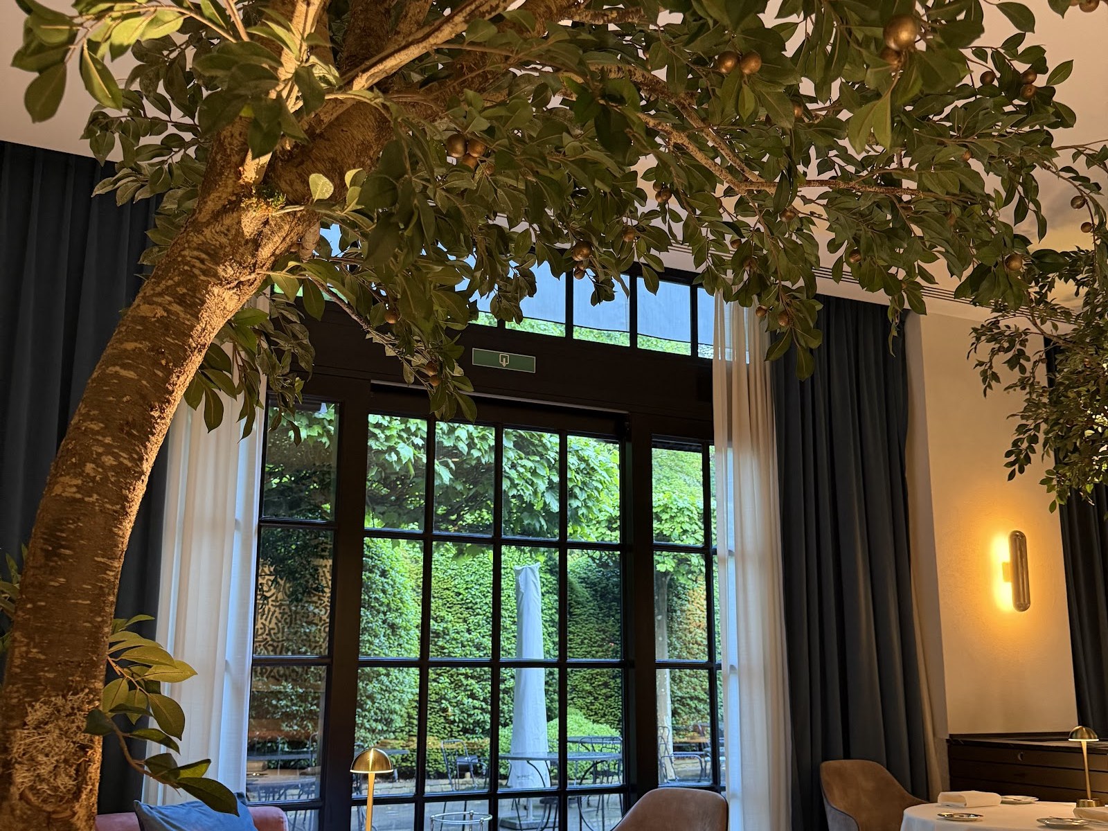 Salle de La Villa Lorraine ouverte par une verrière sur le jardin arboré