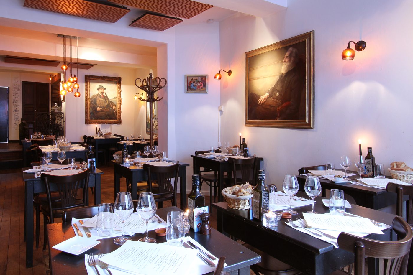 Salle du Wine Bar des Marolles avec tables dressées et tableaux anciens aux murs