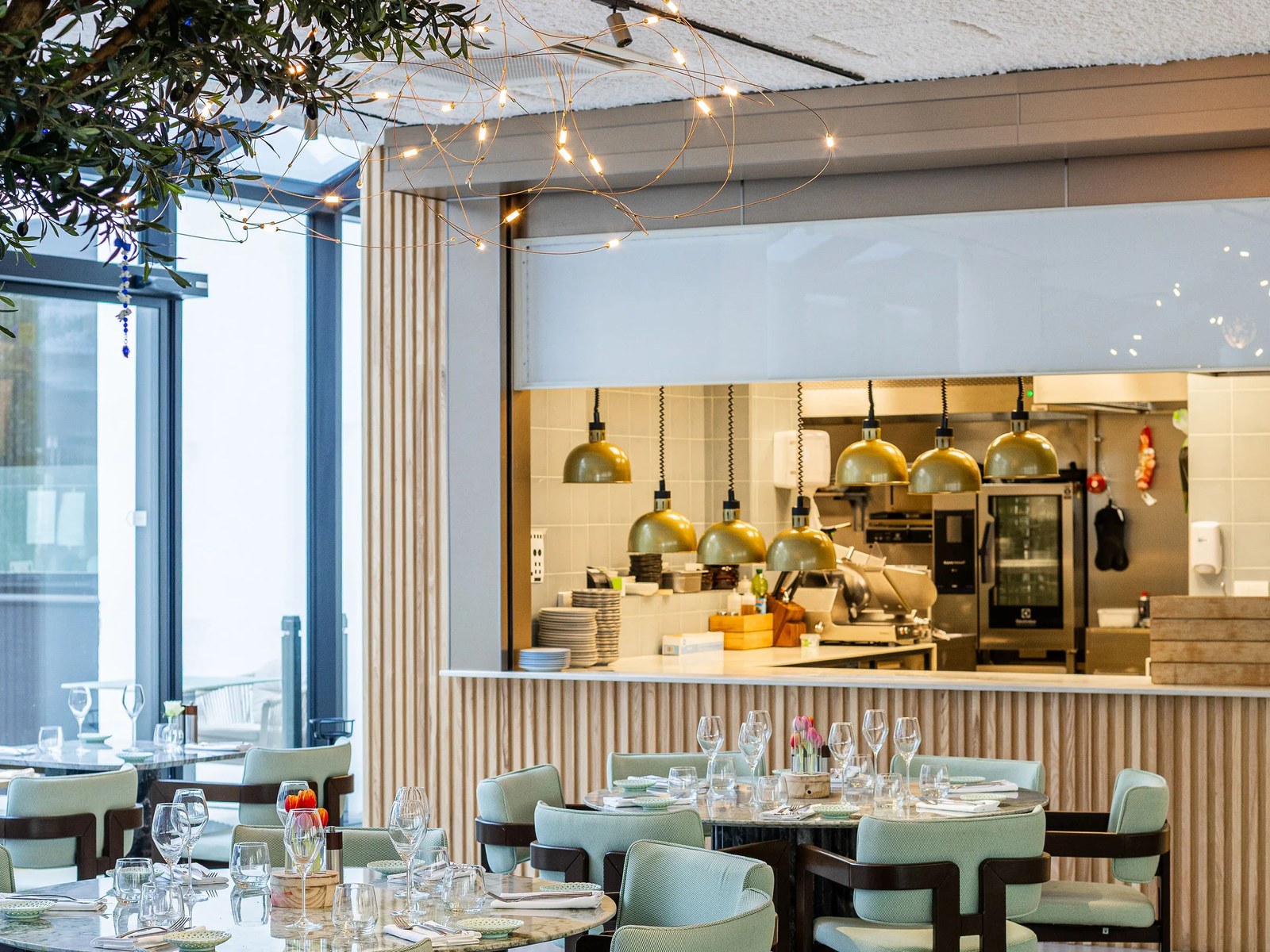 Cuisine ouverte du restaurant Zeyya vue depuis la salle, tables dressées au premier plan